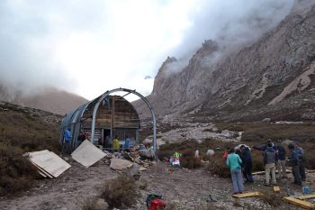 Vista del refugio Portinari con un grupo de personas realizando tareas de mantenimiento